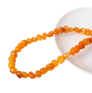 Nahaufnahme unregelmäßiger Bernstein-Achat-Perlen auf Keramiktablett für DIY-Schmuck