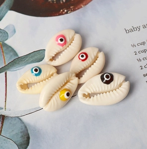 Macro shot of 5 natural shell charms with colorful evil eye patterns for DIY jewelry making