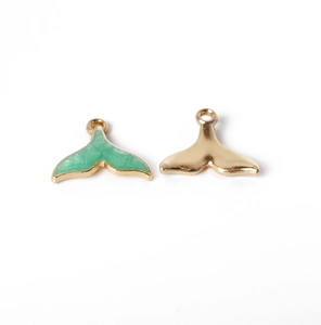 Close-up of alloy whale tail pendants with green marble enamel and polished gold finish