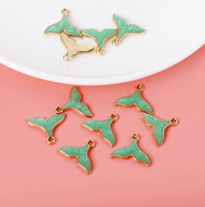Detail of green enamel whale tail pendants with gold edges for DIY jewelry making