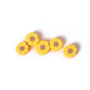 Cinq perles marguerites en pâte polymère jaune pour bijoux DIY sur fond blanc