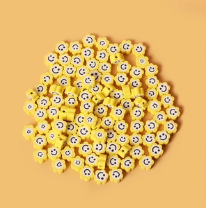 Gros plan de perles fleurs en pâte polymère jaune avec visages souriants pour bijoux DIY