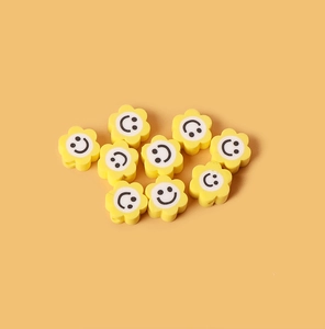 Gros plan de perles fleurs souriantes en argile jaune pour bijoux DIY
