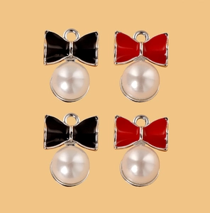 Detail van DIY sieraden bedeltjes met elegante strikjes en glanzende parels in rood en zwart