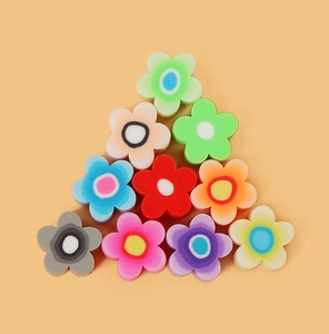 Perles fleurs colorées en pâte polymère pour bijoux DIY sur fond orange vif et épuré