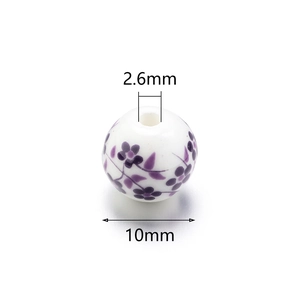 Detail view of 8mm white ceramic bead with purple floral pattern and 2.6mm hole