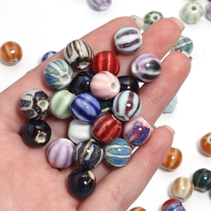 Close-up of hand holding colorful striped ceramic pumpkin beads for DIY jewelry making