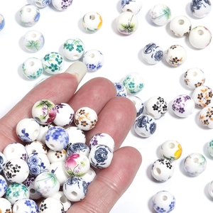 Hand holding assorted blue and white porcelain floral ceramic beads for DIY jewelry