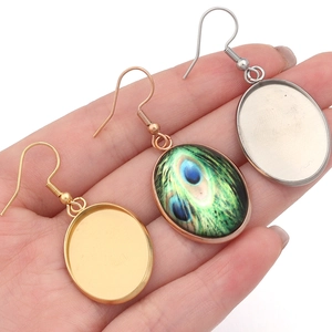 Close-up of teardrop stainless steel earring trays and peacock feather pendant charms
