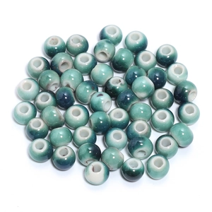 Macro shot of glazed ceramic round beads with teal and cream gradient for DIY jewelry making