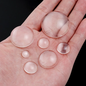 Clear round glass cabochons in various sizes shown on a palm for DIY jewelry making