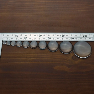 Detailed view of clear glass cabochons in various sizes displayed on a dark wood background