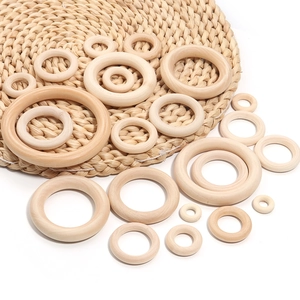 Natural unfinished wooden rings in various sizes for DIY crafts on a woven mat background