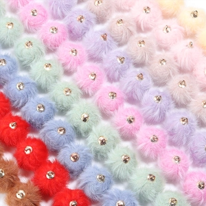 Detalle macro de pompones de piel sintética de 16mm con aros dorados para manualidades