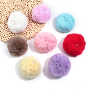 Detail of colorful fluffy faux fur pom-poms with elastic loops on a woven mat