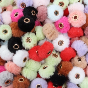 Close-up of colorful faux fur pompom beads with golden eyelets for DIY jewelry making