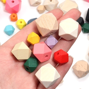 Cuentas geométricas de madera coloridas para manualidades en la mano sobre fondo blanco