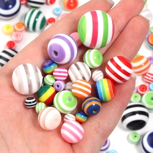 Close-up of colorful striped resin beads in hand for DIY jewelry making accessories