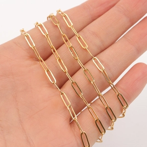 Close-up of golden paperclip chain necklace showing smooth long oval links in hand