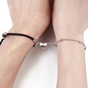 Dettaglio di ciondoli a cuore magnetici su cordino nero e braccialetti con perline d'argento