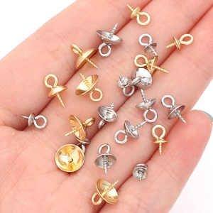 Hand holding silver and gold stainless steel screw eye bails for DIY pearl pendants