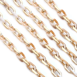 Macro detail of gold metal links and beige marble acrylic rings in a layered chain