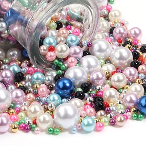 Macro shot of colorful mixed size faux pearls spilling from a glass jar for DIY crafts