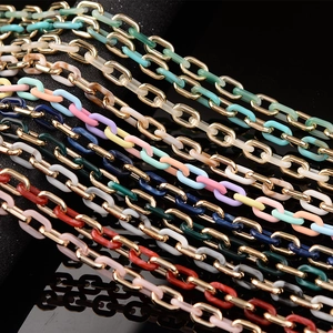 Macro detail of interlinked colorful acrylic and gold metal chain links on black display