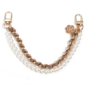 Detail of camellia flower charm and gold metal chain with pearl strap for bags