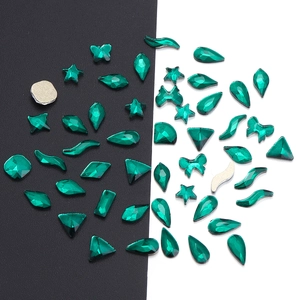 Macro shot of emerald green flatback glass crystals in various shapes for nail art DIY