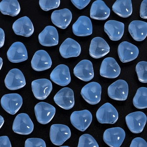 Macro shot of light blue heart-shaped glass beads with vertical holes for DIY jewelry