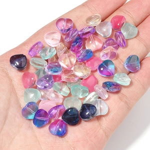 Colorful gradient glass heart beads for DIY jewelry making held in a palm for scale