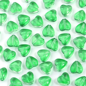 Close-up of translucent emerald green glass heart beads with a central hole for DIY jewelry