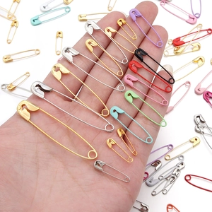 Assorted colorful painted gourd safety pins in various sizes held in hand for DIY crafts