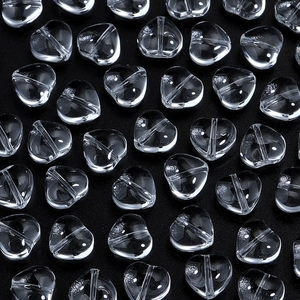 Macro shot of transparent heart-shaped glass beads with hole for DIY jewelry making