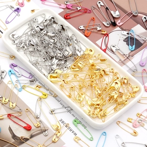Close-up of colorful iron safety pins in various sizes on a white ceramic tray