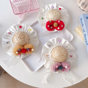 Detailed view of mini straw hats with colorful pom-poms and large plush bows for pets