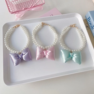 Close-up of double-row pearl pet collars with rhinestone bows in pastel colors