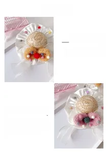 Close-up of pet straw hat with chiffon flowers, plush balls and white satin edging