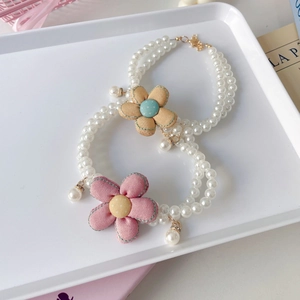 Detail of cream pearl pet necklace with stitched fabric flowers and gold lobster clasp
