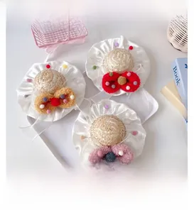 Detail of handmade pet straw hats with colorful plush bows and ruffled lace edges