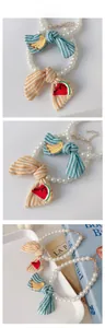 Close-up of pearl bead necklaces with striped bows and fruit embroidery for pets