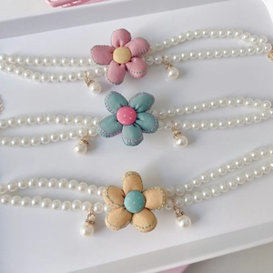 Detail of double-layer pearl necklaces featuring pink, teal, and yellow fabric flowers