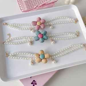 Close-up of double-layer pearl pet necklaces with colorful fabric flowers and metal clasps