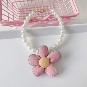Close-up of pearl pet necklace with pink fabric flower pendant and gold lobster clasp