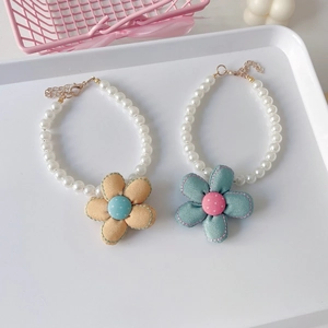 Detail of pet pearl necklaces with colorful fabric flowers and adjustable gold clasps