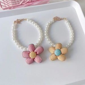 Close-up of double-layer pet pearl necklace with pink fabric flower and golden chain clasp