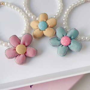 Macro shot of double-layer pet necklaces with fabric flowers and high-gloss pearls