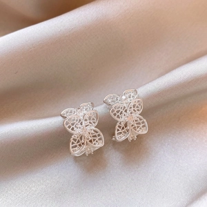 Vista detallada de elegantes pendientes plateados en forma de C con diseño floral calado