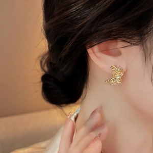 Primer plano de elegantes pendientes de botón de flores caladas en oro con circonitas en un modelo